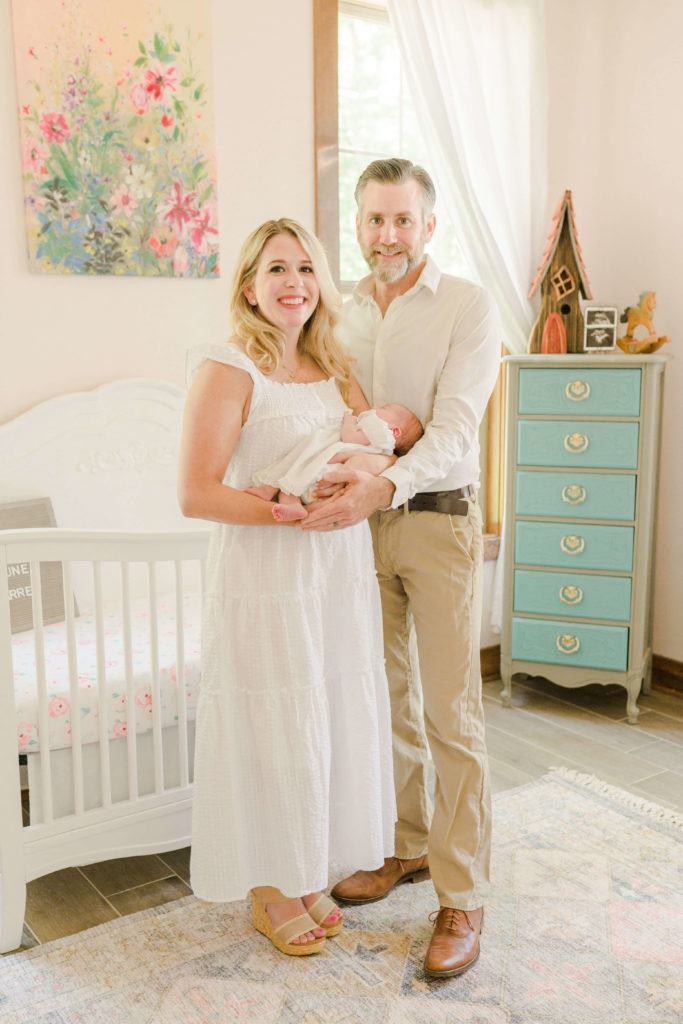 Mom, dad and baby in nursey during newborn session