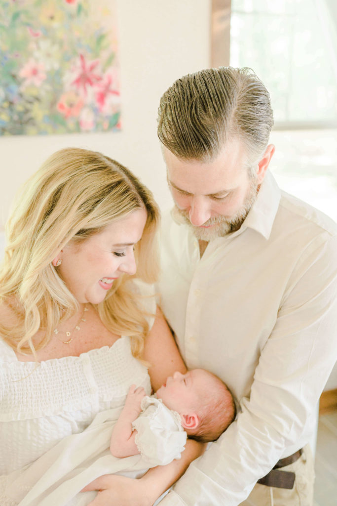 Mom and dad smiling at sleeping baby during lifestyle session