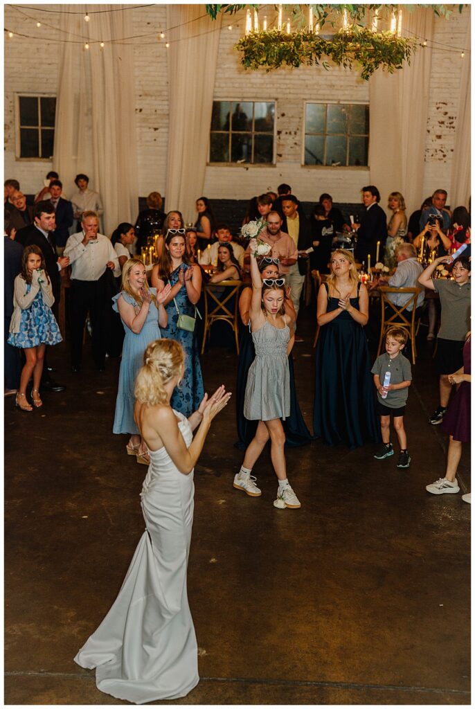 Bride tosses flowers to guests during Anna and John Parker’s wedding reception at The Raymond Venue in Mississippi